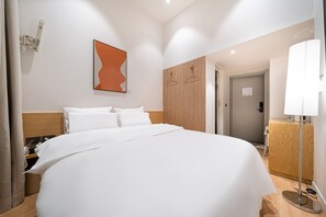 Ein Hotelzimmer mit einem großen Bett, einem Holzkopfstück, einem an der Wand befestigten abstrakten Kunstwerk, einer Wand aus Holzpaneelen, einem Nachttisch und einer Lampe.