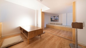 Een moderne kamer met een houten bureau, een bankje en een hoge plafond.