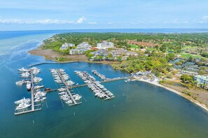 An aerial view of a marina with multiple docks and boats, surrounded by residential buildings and greenery.