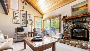 A cozy living room with a stone fireplace, comfortable seating, and framed pictures on the wall.