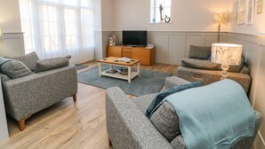 A living room with a sofa set, a coffee table, a TV, and a lamp.