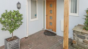 Et hus med dør i træ, en lille veranda og en potteplante.