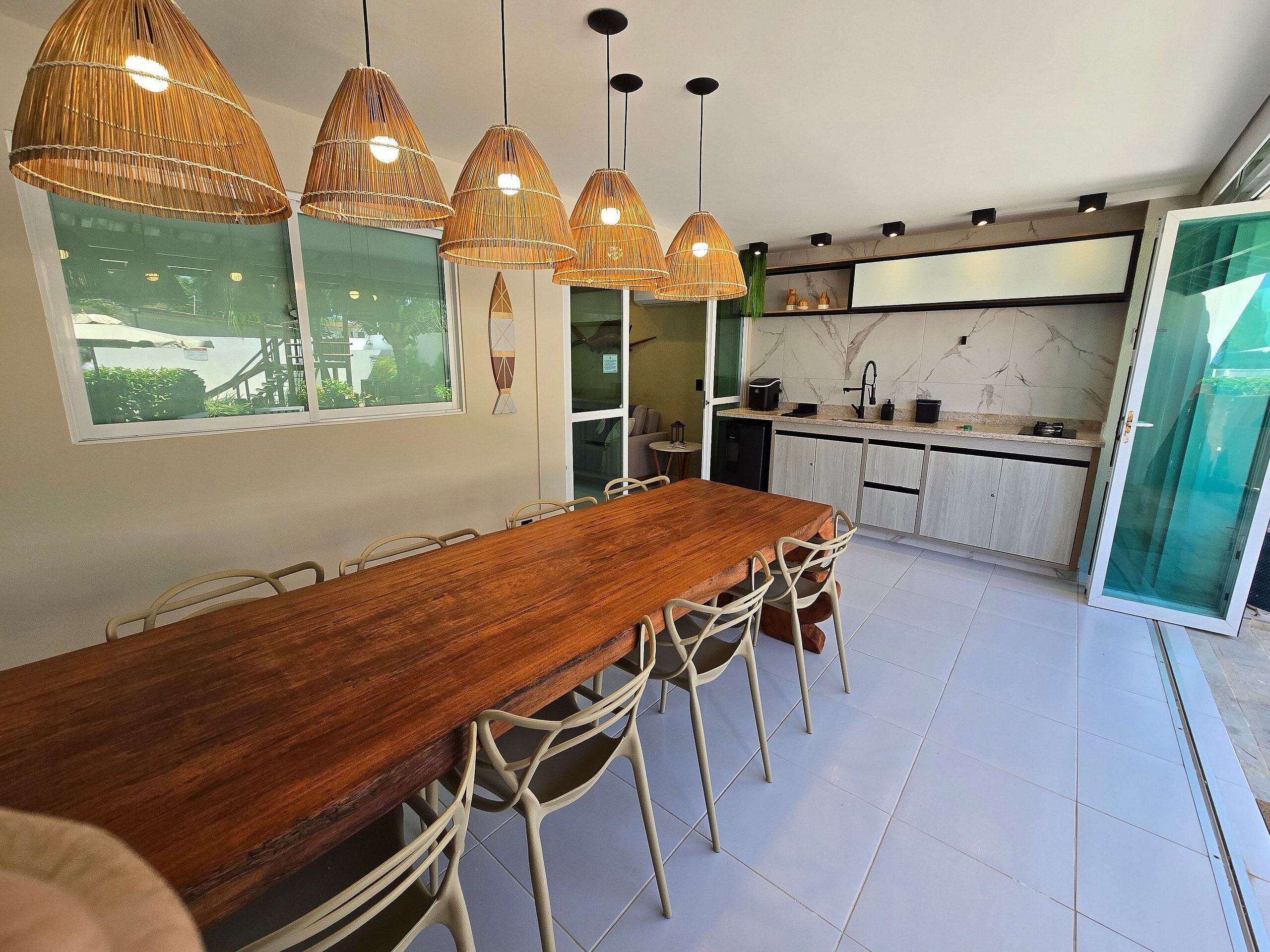 Uma cozinha moderna com uma mesa e cadeiras de madeira, forno embutido e uma janela grande.