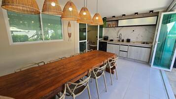 Uma cozinha moderna com uma mesa e cadeiras de madeira, forno embutido e uma janela grande.