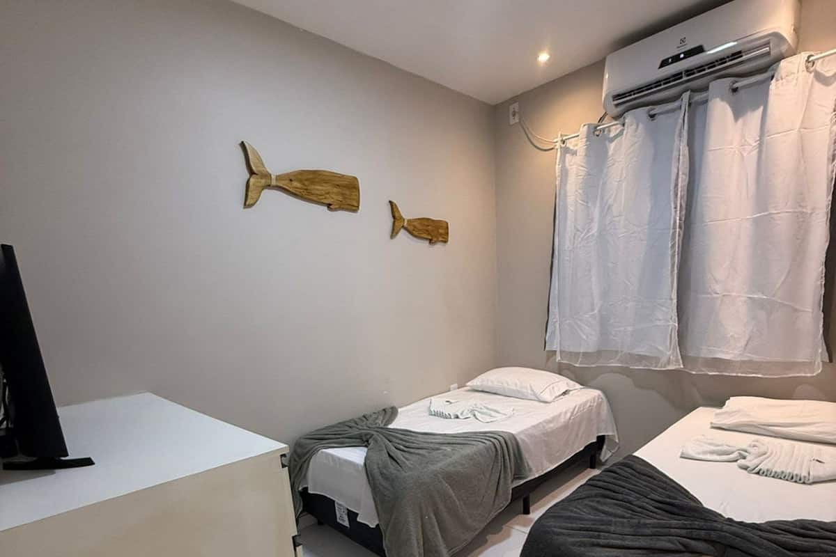 A hotel room with two beds, a desk, and a ceiling fan.