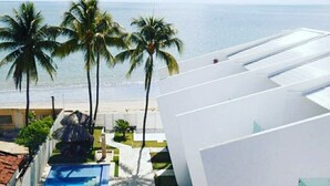 A modern hotel with a pool, palm trees, and a view of the ocean.