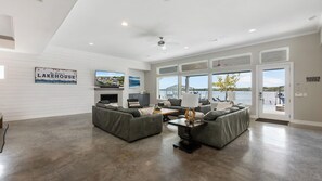 A spacious living room with a fireplace, large windows, and a view of the lake.