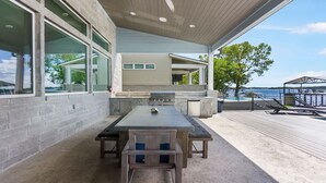 An outdoor patio with a grill, seating, and a view of the water. - Bud Bliss Retreat | Concierge Services (Kingsland)