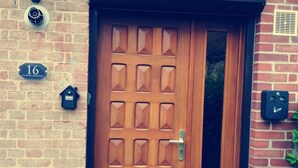 A wooden door with a grid pattern, a mailbox, and a house number sign on a brick wall. - Spa Privatif Jacuzzi et Sauna, Maison de Ville 4 Personnes (Yerville)