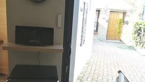 A room with a Marshall amplifier, a clock on the wall, and a view of a brick-paved courtyard through an open door. - Spa Privatif Jacuzzi et Sauna, Maison de Ville 4 Personnes (Yerville)