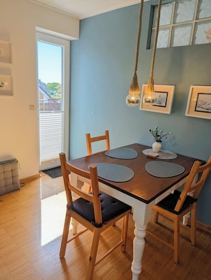 A dining area with a wooden table, four chairs, and a hanging light fixture.