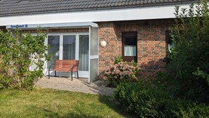 Ein Haus mit einer Veranda, einer Bank und einem kleinen Garten.