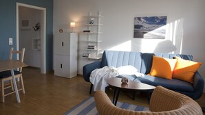 Ein modernes Wohnzimmer mit einem blauen Sofa, einem Esstisch und einem Bücherregal.