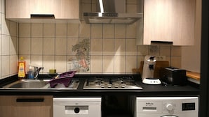 Una cocina equipada con estufa a gas, cafetera, lavavajillas y lavadora.