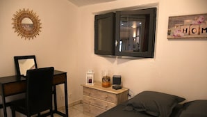 Un dormitorio con cama, escritorio, silla, cómoda, espejo, ventana y decoración en la pared.