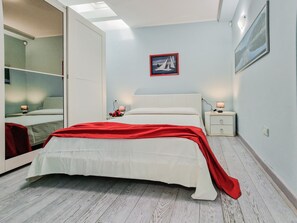 Quarto com cama, mesas de cabeceira, espelho e um quadro na parede.