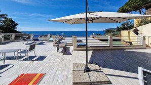 Terraza con sillones y sombrillas, con vista al mar.