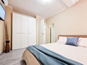 Un dormitorio con cama, armario y puerta que da a otra habitación.