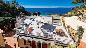 Una terraza en la azotea con mobiliario exterior y vista al mar.