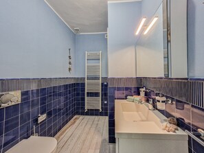 Casa de banho com sanita, lavatório, espelho e porta-toalhas.