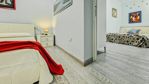 Un dormitorio con una cama, una mesita de noche, una lámpara y una puerta que da a otra habitación.