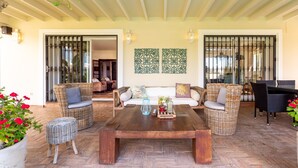 A spacious patio with wicker furniture, a wooden coffee table, and decorative wall art. - 'Luxury Villa Larios Torrequebrada' with Sea View, Pool & Wi-Fi (Benalmádena)