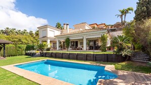 A swimming pool with a tiled deck, a house with a tiled roof, and a well-maintained garden with palm trees. - 'Luxury Villa Larios Torrequebrada' with Sea View, Pool & Wi-Fi (Benalmádena)