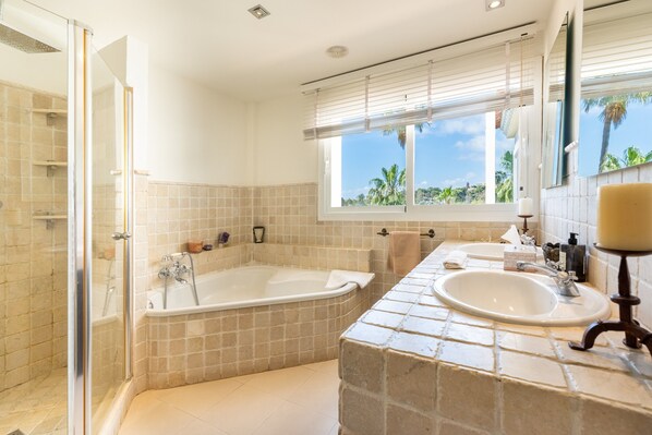 A bathroom with a glass-enclosed shower, a freestanding bathtub, and a sink with a vanity.