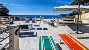Eine Dachterrasse mit Liegestühlen, einem Pool und Blick aufs Meer.