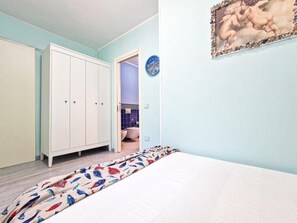 Una camera da letto con un letto, un armadio, un bagno parzialmente visibile attraverso una porta aperta e un quadro appeso al muro.