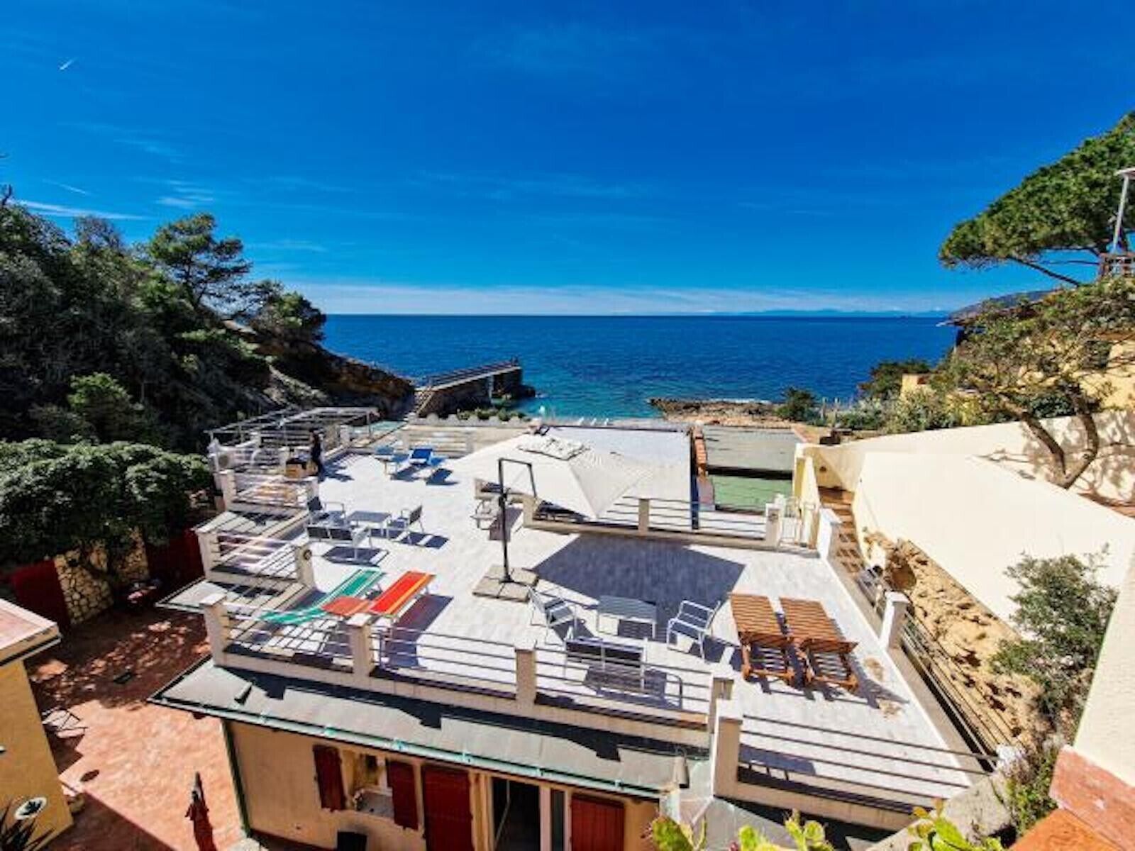 Une terrasse sur le toit, dotée de chaises longues et offrant une vue sur la mer.