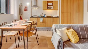 A compact living space with a dining area, kitchenette, and a sofa. - Apartment "Calheta Lofts I" with Mountain View, Private Balcony & Wi-Fi (Lombo Do Doutor)