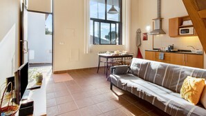 A modern kitchen with a microwave, a dining table, and a sofa in a well-lit living area. - Apartment "Calheta Lofts I" with Mountain View, Private Balcony & Wi-Fi (Lombo Do Doutor)