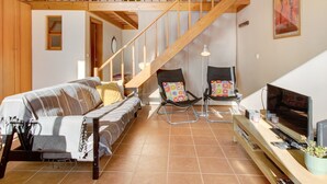 A living room with a sofa, two chairs, a TV, and a staircase. - Apartment "Calheta Lofts I" with Mountain View, Private Balcony & Wi-Fi (Lombo Do Doutor)