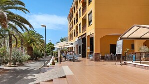 Ein Hotel mit Außenbereich, Palmen und einer gelben Gebäudefassade.