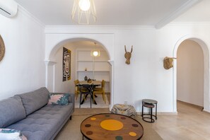 A living room with a sofa, a round coffee table, and a dining area with a table and chairs.