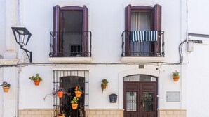 Ein zweistöckiges Gebäude mit einer braunen Tür, zwei Fensterläden und einem Balkon mit einem gestreiften Handtuch.