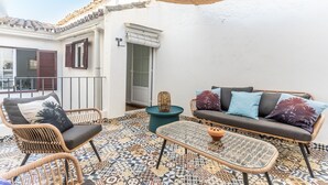 Ein Balkon mit Korbmöbeln, einem gemusterten Boden und einem Deckenventilator.