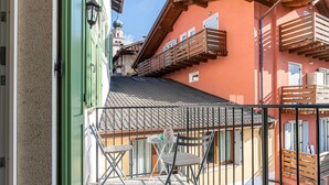 Ein Balkon mit Tisch, Stühlen, Geländer und Blick auf benachbarte Gebäude.