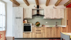 Eine moderne Küche mit Holzschränken, einem eingebauten Backofen und einer Edelstahl-Dunstabzugshaube.