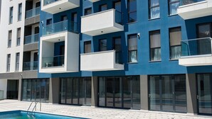 Um edifício moderno com varandas, piscina e céu claro.