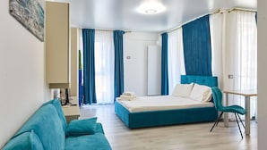 Um quarto moderno com uma cama grande, um sofá, uma escrivaninha e uma cadeira.