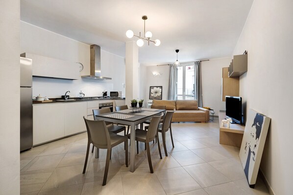 A modern kitchen with a dining table, chairs, and a TV.