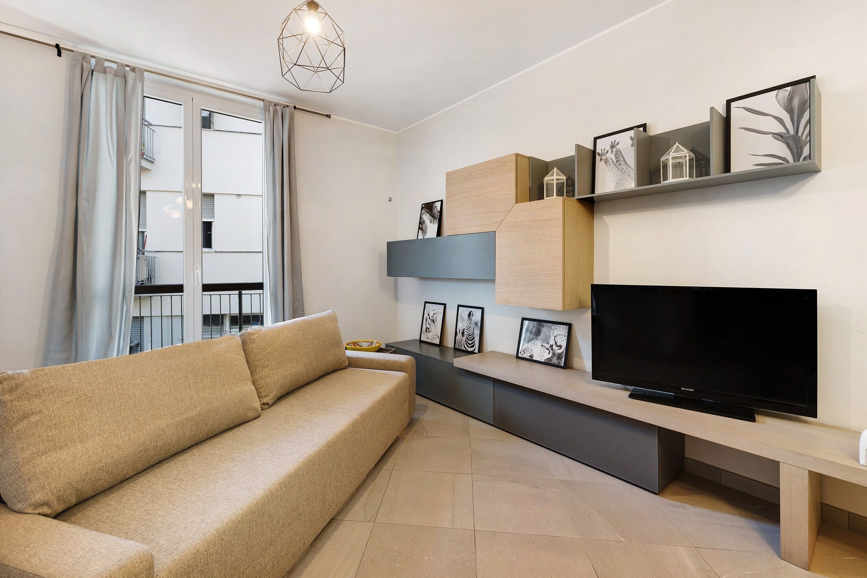 A modern living room with a sofa, TV, and wall-mounted shelves with pictures.