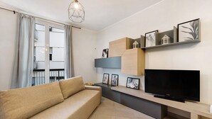 A modern living room with a sofa, TV, and wall-mounted shelves with pictures. - Vacation Apartment '4 Passi Mare 2' with Balconies, A/C and Wi-Fi (Finale Ligure)