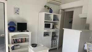 Kompakti oleskelutila, jossa on televisio, kirjahylly, mikroaaltouuni ja pieni pöytä.