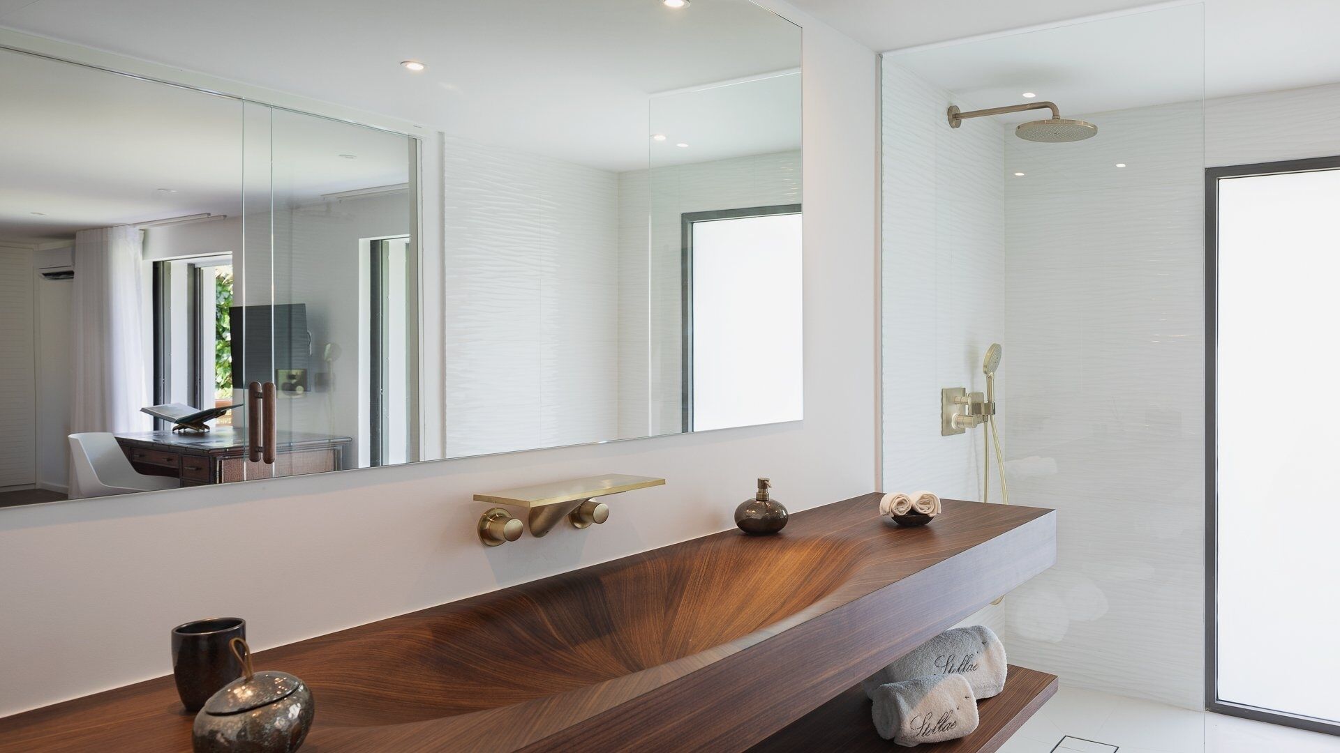 A modern bathroom with a wooden vanity, a large mirror, a shower with a handheld showerhead, and a towel rack.