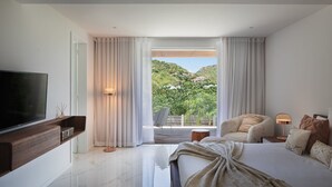 Une chambre moderne avec un grand lit, une télévision et une vue sur un jardin luxuriant.