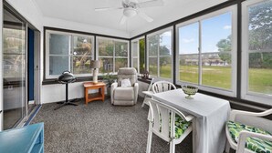 A sunroom with a ceiling fan, large windows, a table with chairs, and a small side table with a lamp. - The Lake Home - Beautiful Oasis In The Heart Of Florida! 2 Bedroom Home by RedAwning (Haines City)