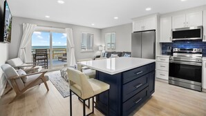 A modern kitchen with a large island, stainless steel appliances, and a view to the outside. - Leeward Ii-3-front Row 1 Bedroom Condo by RedAwning (Santa Rosa Beach)